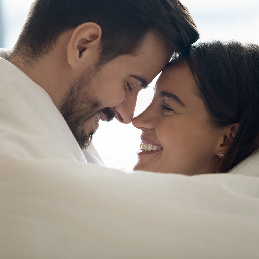 Close up profile faces happy Hispanic woman Caucasian man mixed race couple cuddling touch foreheads covered in warm blanket enjoy romantic weekend. Hotel and tourists newly-weds, heat system concept