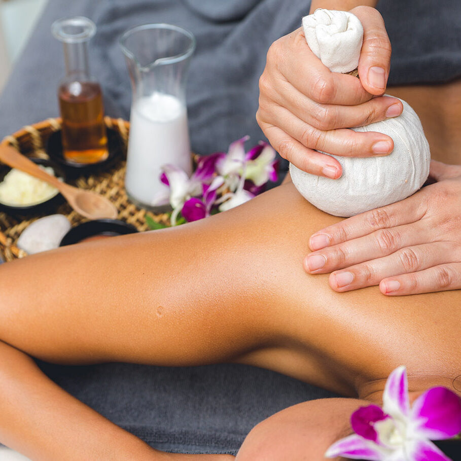 Thai Massage of  asian woman in spa room. Beautiful young woman having massage with herbal compress balls in therapy spa salon.