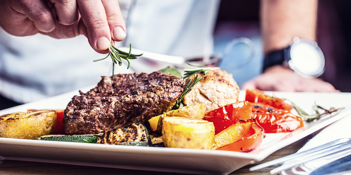 Chef in hotel or restaurant kitchen cooking only hands. Prepared beef steak with vegetable decoration.Chef in hotel or restaurant kitchen cooking only hands. Prepared beef steak with vegetable decoration.