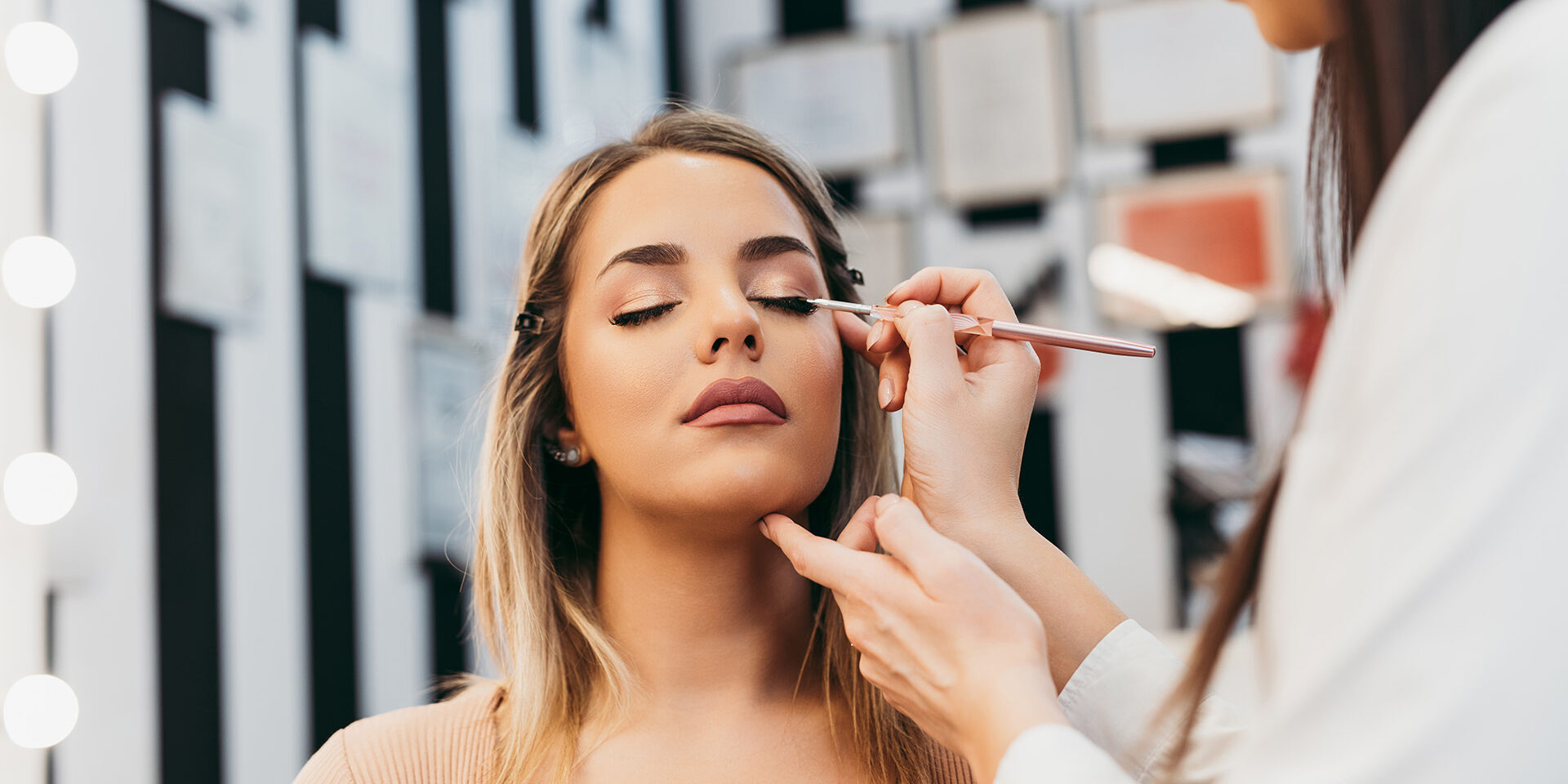 Professional makeup artist doing professional make up of beautiful young woman.