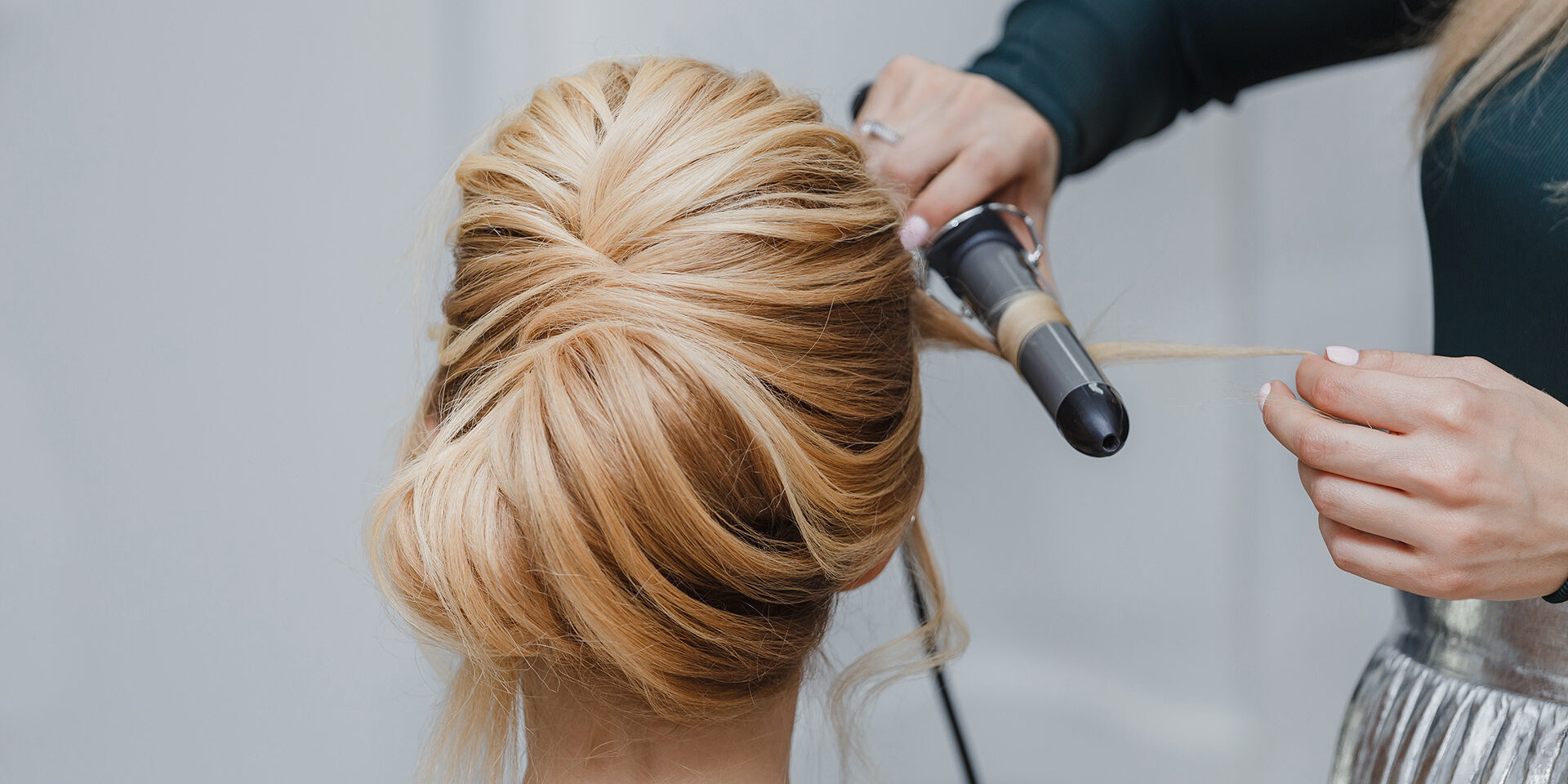 closeup of professional hairdresser hands doing beauty hairstyle a-la french twist