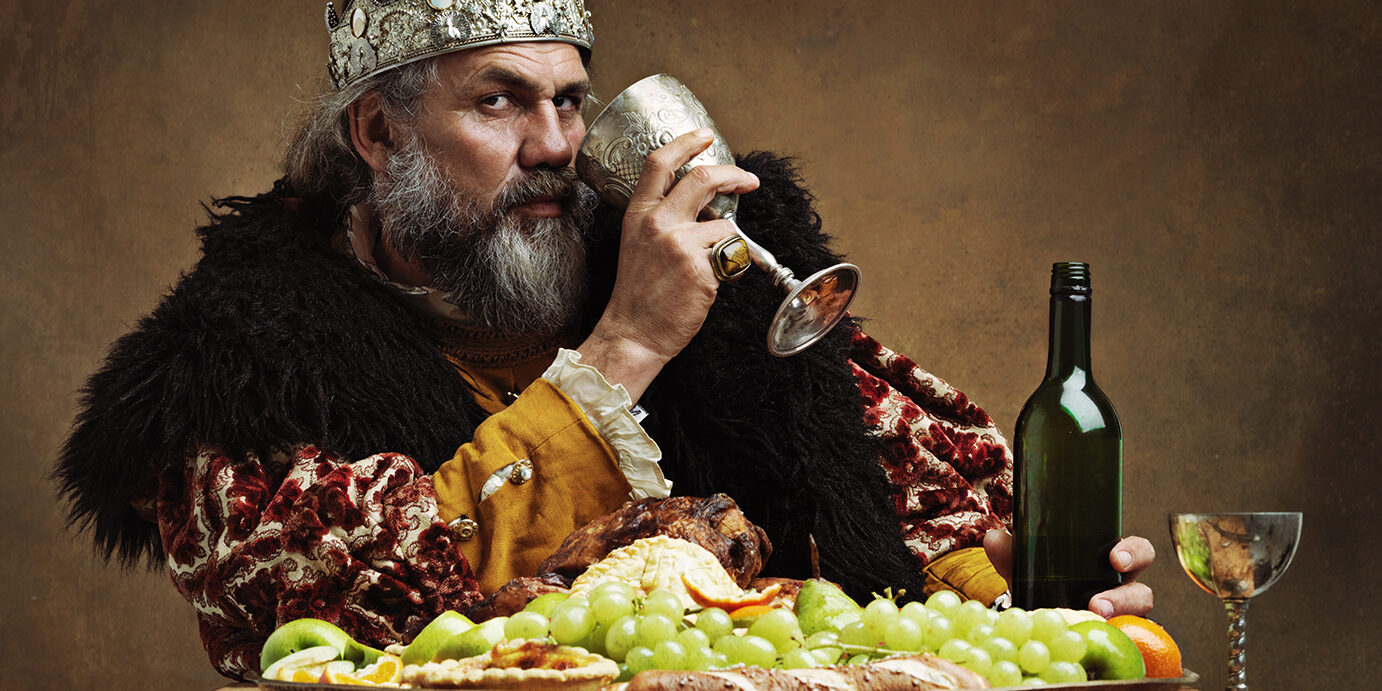 A mature king feasting alone in a banquet hall