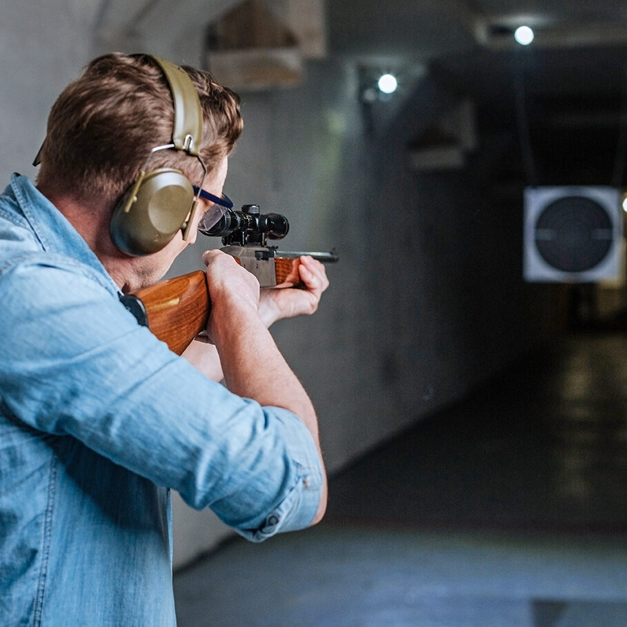 Hitting the bulls eye. Handsome confident serious man holding the rifle and looking into the target while trying to hit the bulls eye