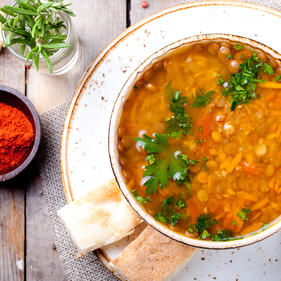 Lentil soup with smoked paprika and bread in a ceramic bowl on a wooden background