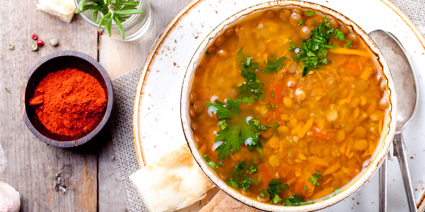 Lentil soup with smoked paprika and bread in a ceramic bowl on a wooden background