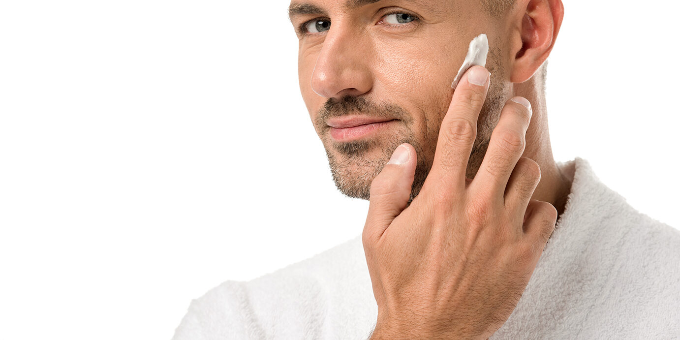 adult handsome man in bathrobe applying beauty cream on face isolated on white adult handsome man in bathrobe applying beauty cream on face isolated on white