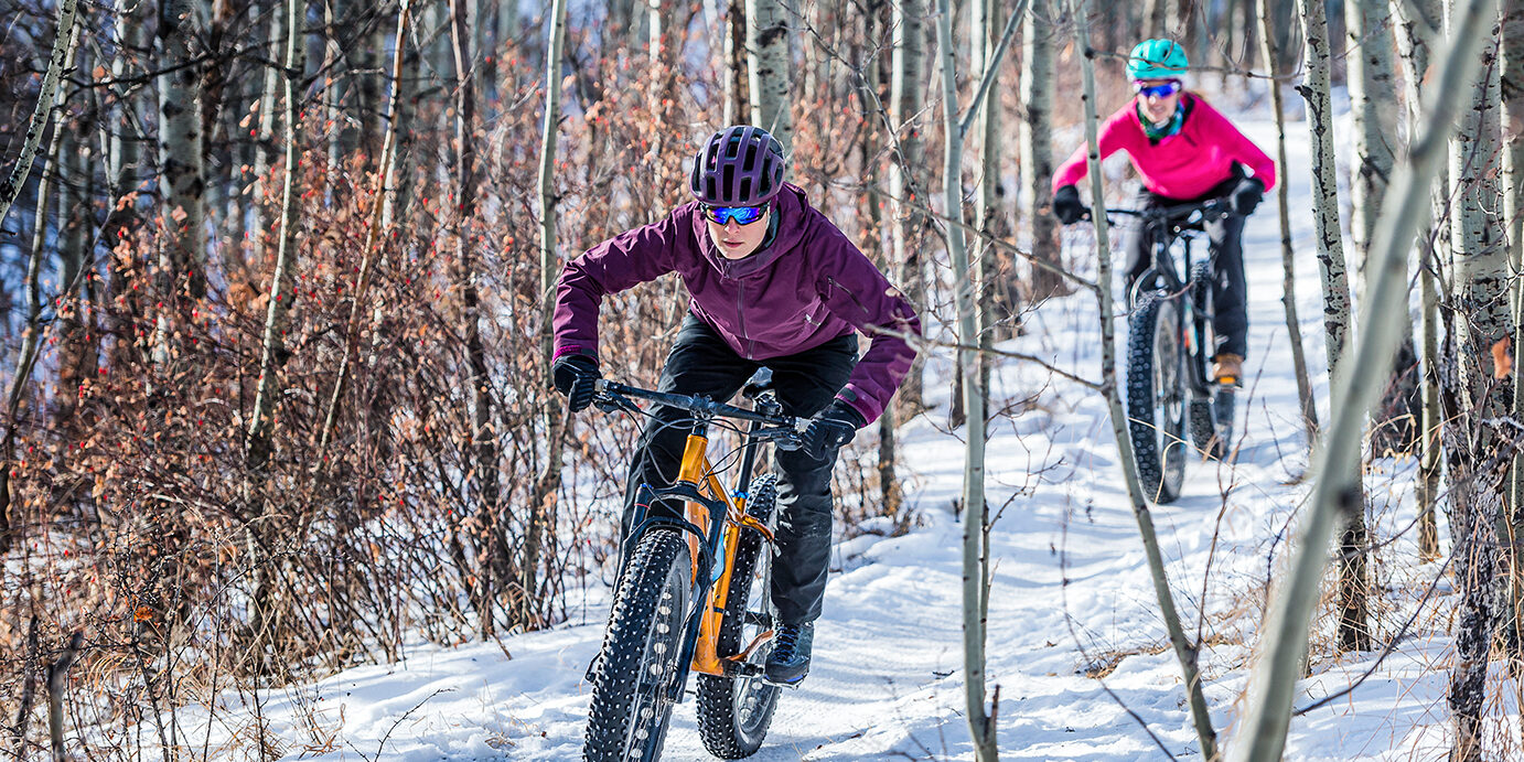 Two Women riding Fatbikes in the Snow two female athletes riding fat bikes in the snow