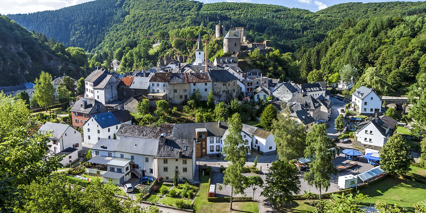 Esch-sur-Sure is a small town near Luxembourg city that sits in a little circle of land within a sharp curve of the river Sure. It is very picturesque and has the ruins of an old castle on top of the hill. The town is surrounded by lush, green trees.