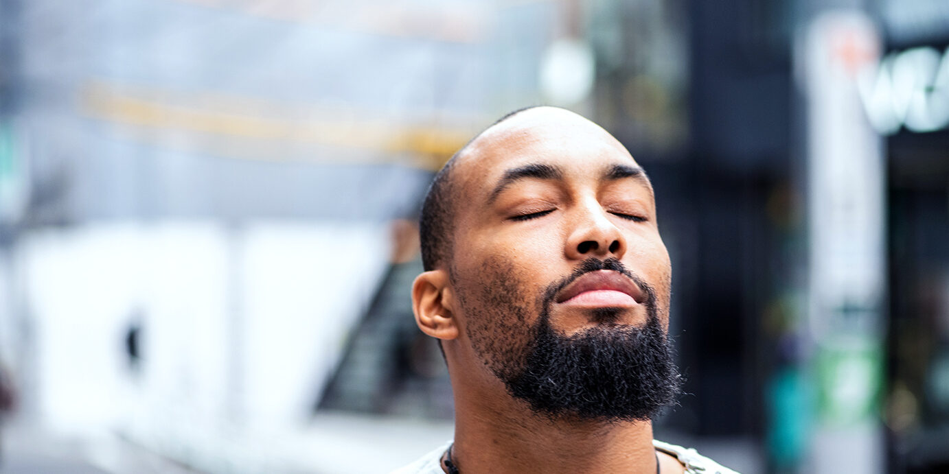 A moment of serenity A handsome man standing outside with his eyes closed, enjoying a moment of peace.