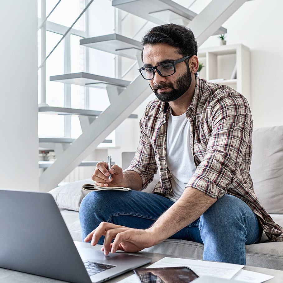 Young indian man student or distance employee working online from home office, e learning using laptop computer watching remote webinar training class, having virtual video call meeting in homeoffice.