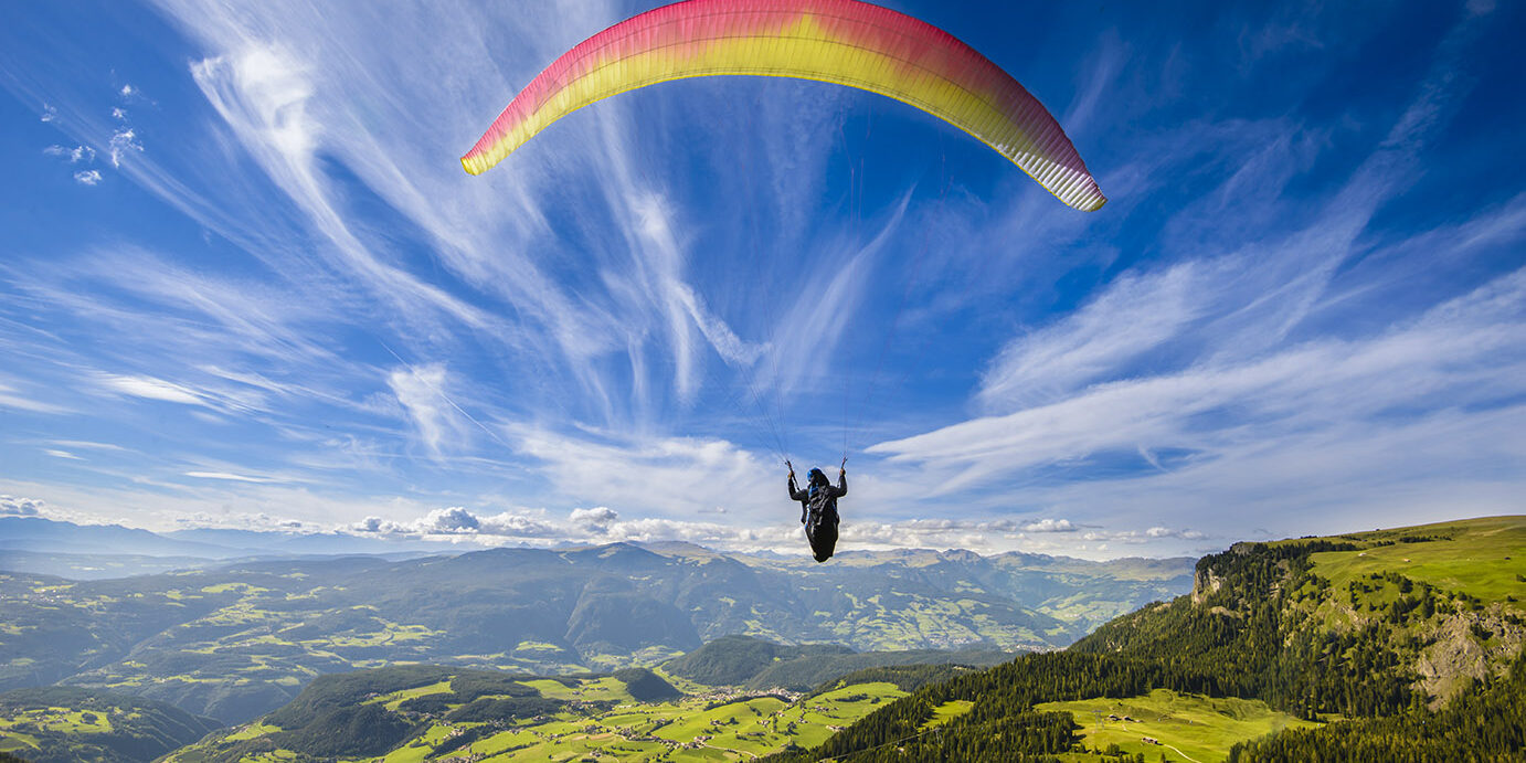 Paraglider flying over mountains in summer day