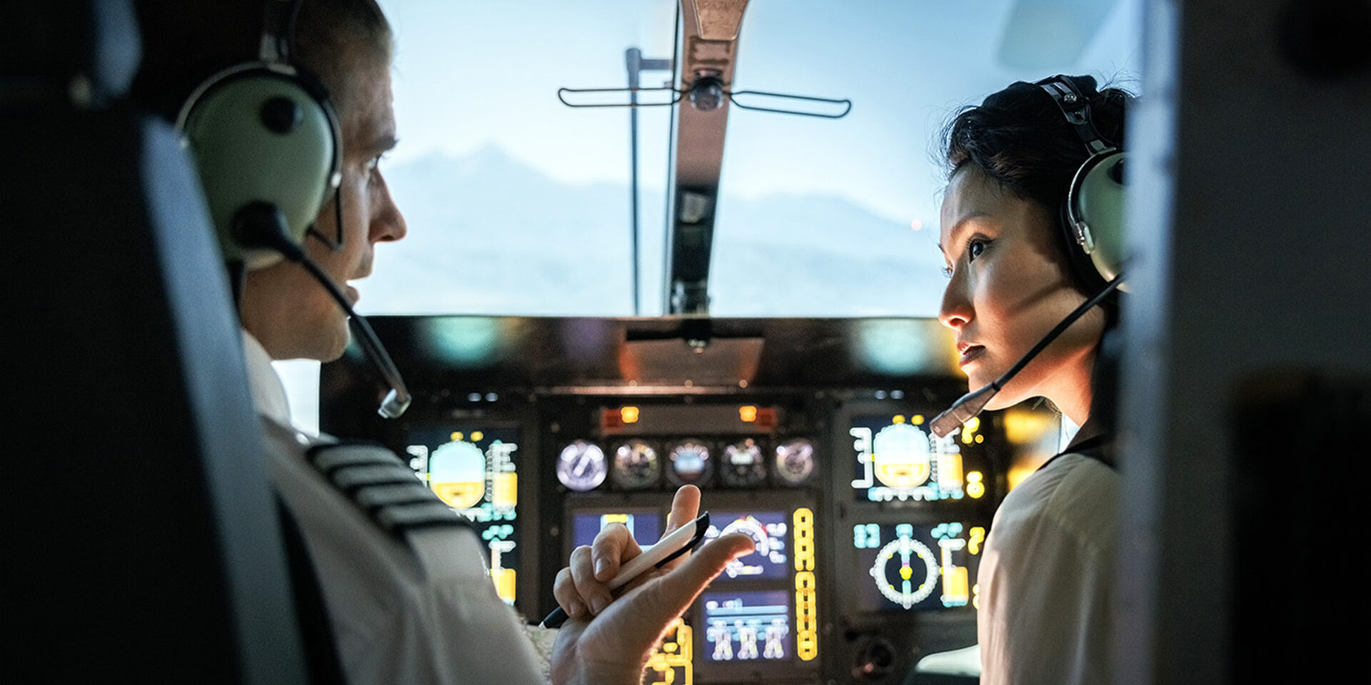 Female trainee pilot listening to instructor during a flight simulation training Female trainee pilot listening to instructor during a flight simulation training. Woman learning to fly helicopter with instructor inside a flight simulator.