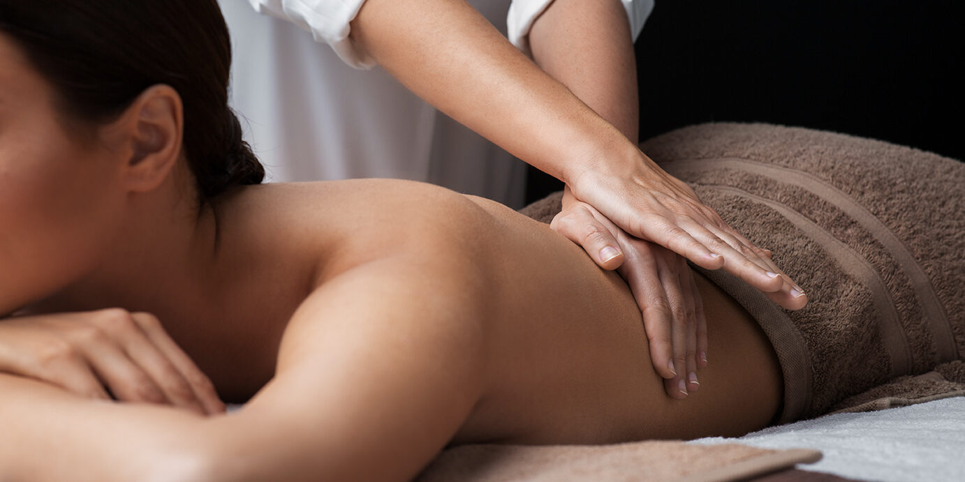 wellness, beauty and relaxation concept - beautiful young woman lying and having back massage at spa