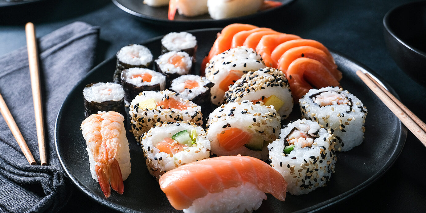 Lunch at the sushi bar Set of sushi and rolls Lunch at the sushi bar. Set of sushi and rolls unagi maki on a black plate on dark background top view. Sushi Delivery to Home Order Online. Takeout coronavirus food.