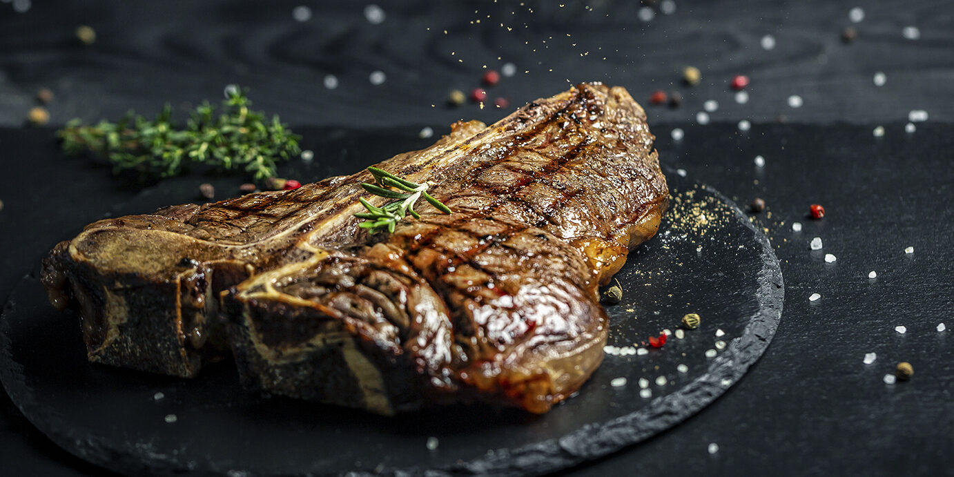 T-bone grilled beef steak. Dry Aged Barbecue Porterhouse Steak. Medium rare. American cuisine. Long banner format, top view T-bone grilled beef steak. Dry Aged Barbecue Porterhouse Steak. Medium rare. American cuisine. Long banner format, top view.