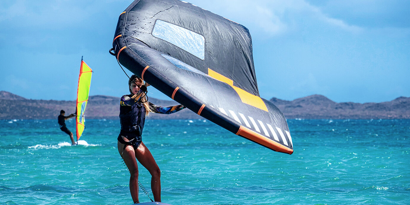 Caucasian young woman practicing wingfoil surf on the ocean