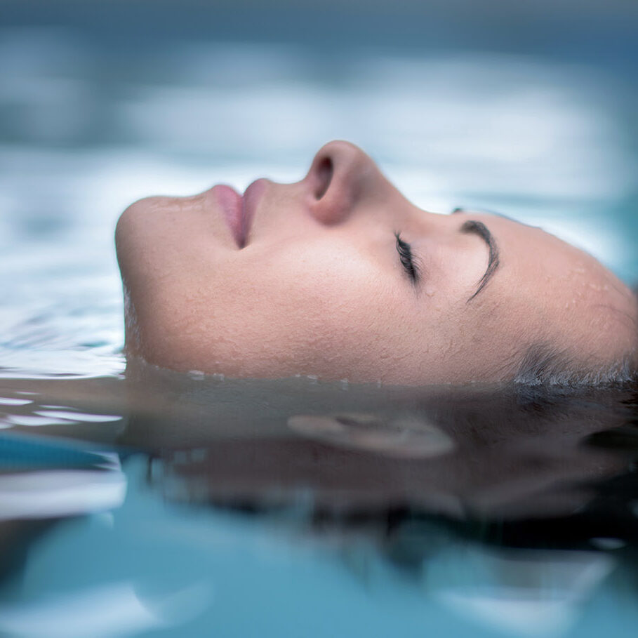 Woman at the spa relaxing at the swimming pool floating with eyes closed