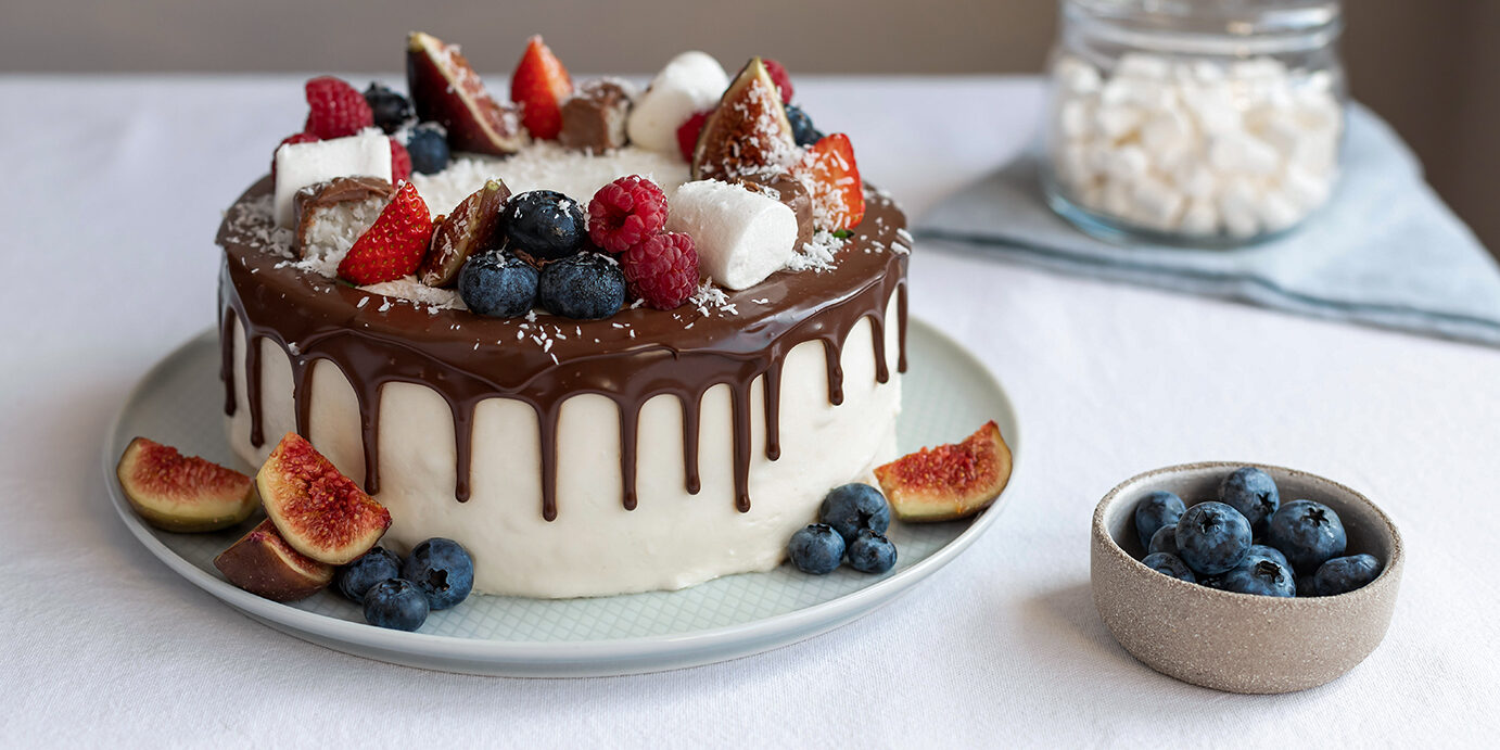 berry cake decorated with marshmallows and chocolate ganache closeup of berry cake decorated with marshmallows and chocolate ganache on white tablecloth. Birthday, Mothers Day concept. Modern dessert