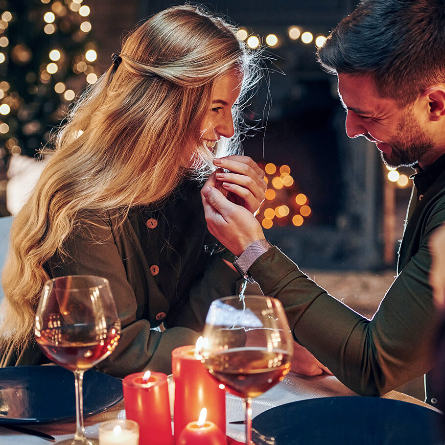 Side view. Young lovely couple have romantic dinner indoors together.