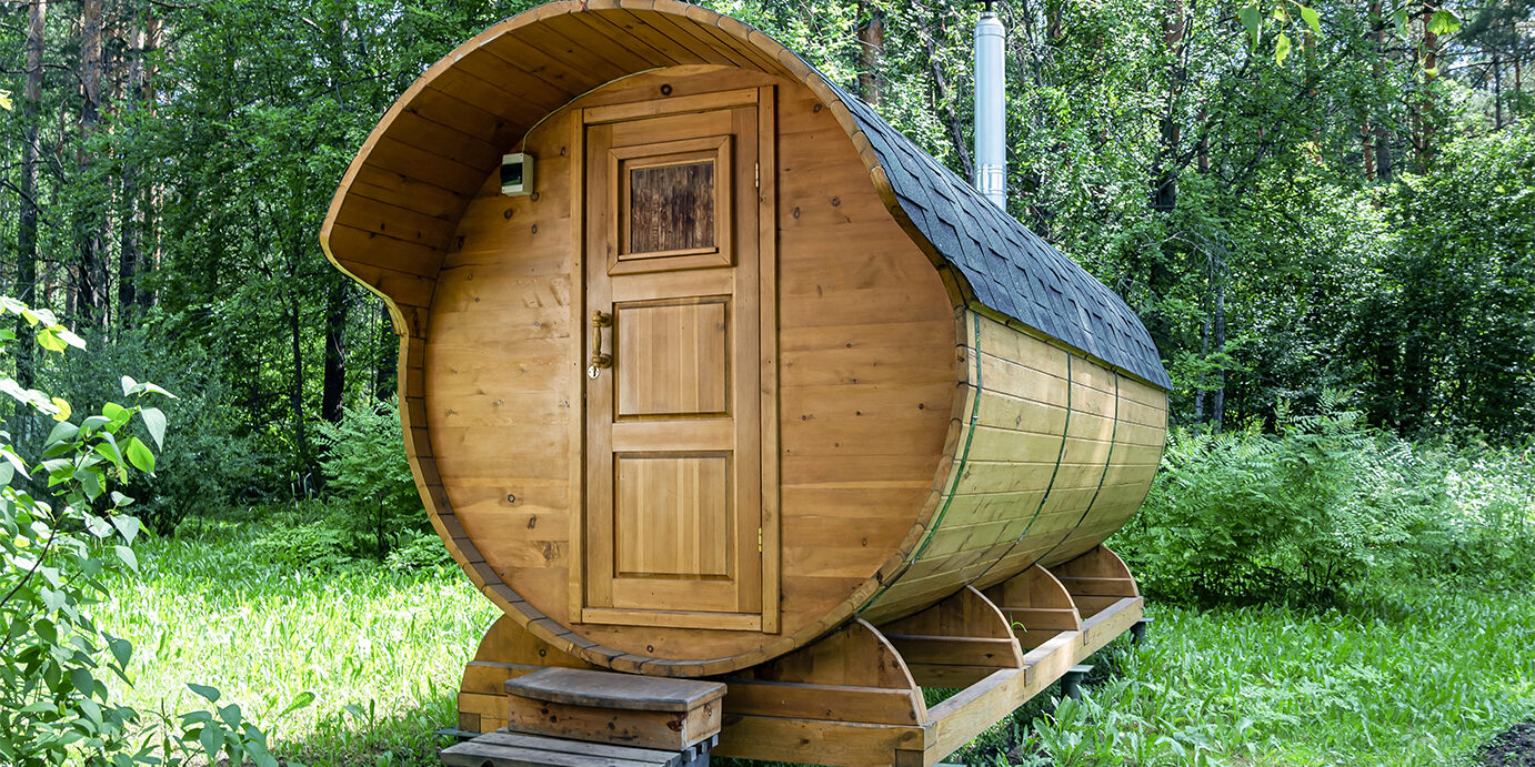 Round wooden barrel bath stands in the forest on a sunny summer day