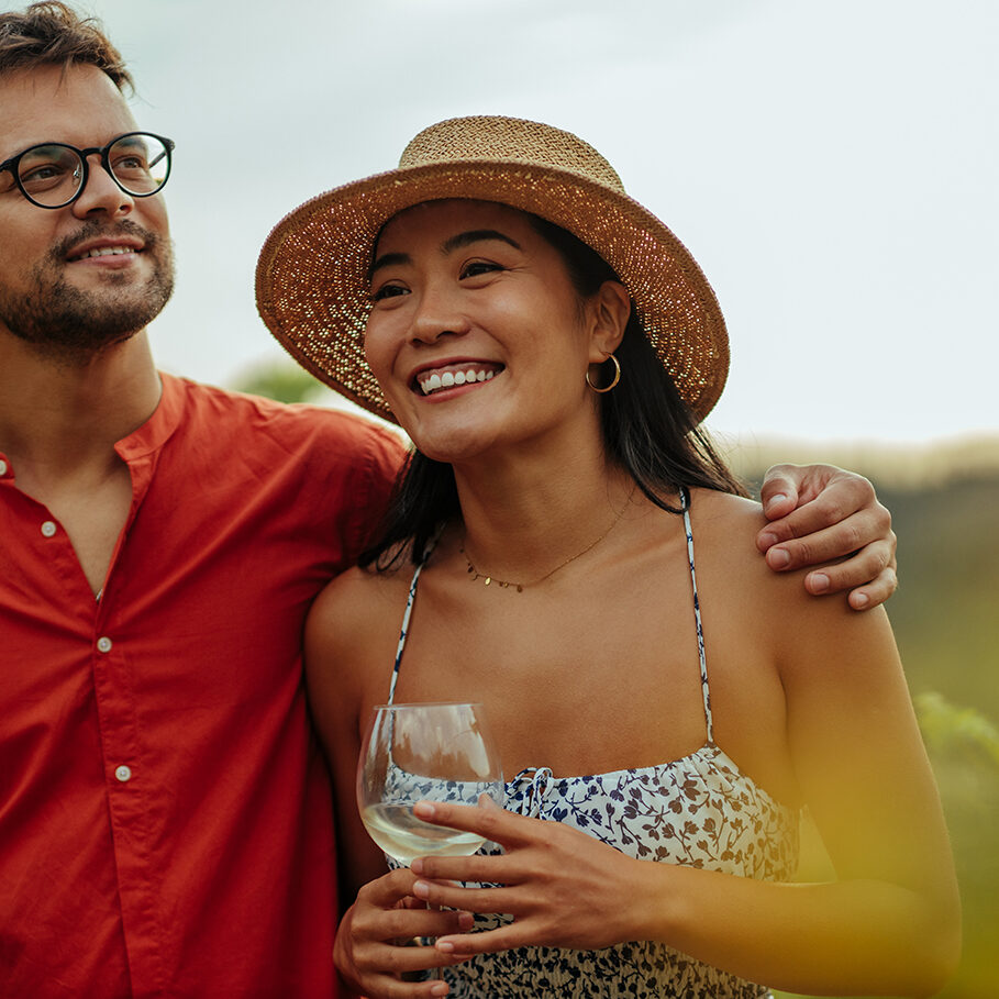 Diverse couple enjoying a glass of wine while walking through the vineyard