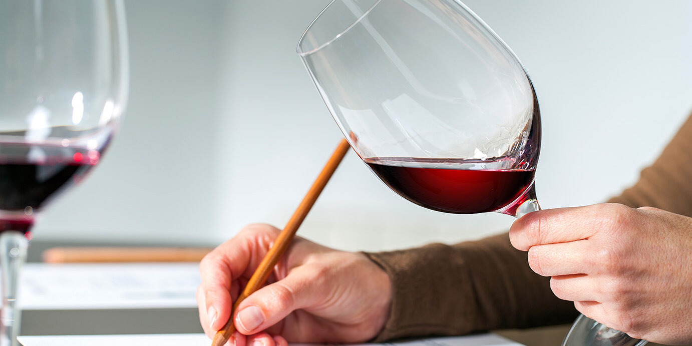 Sommelier evaluating red wine. Extreme close up of sommelier evaluating red wine in wine glass at tasting.