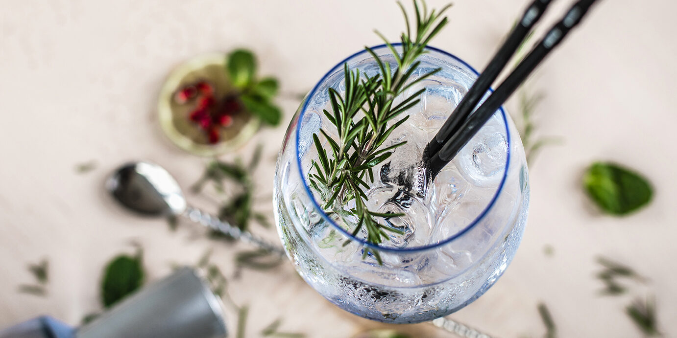 Gin Soda with a Rosemary Decorated Gin Soda with a Rosemary Leaf on a wooden desk