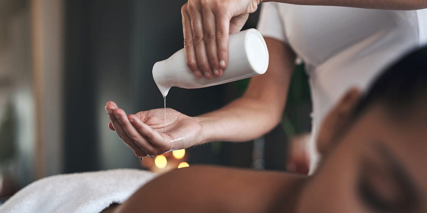 Closeup shot of a massage therapist pouring body oil into her hands while giving a massage to a customer at a spa This soothing massage oil will work wonders