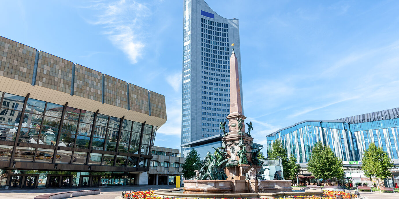 Famous Mende Fountain - Mendebrunnen - with Gewandhaus Concert Hall and tall University Tower at the Augustusplatz in Summer. Leipzig, Saxony, Germany