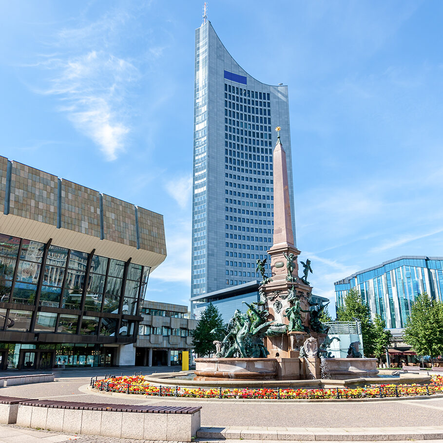 Famous Mende Fountain - Mendebrunnen - with Gewandhaus Concert Hall and tall University Tower at the Augustusplatz in Summer. Leipzig, Saxony, Germany