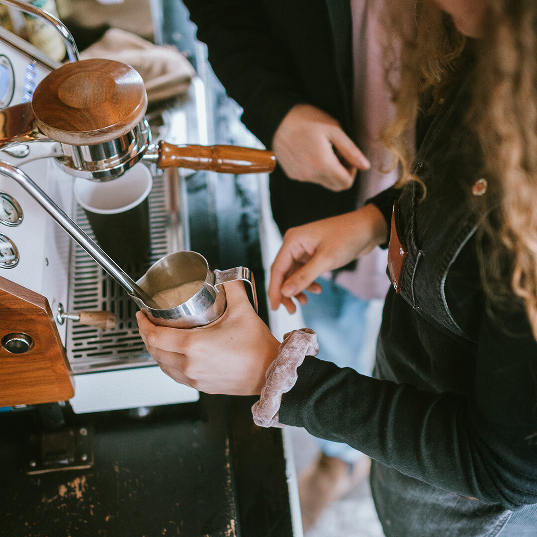 Training time for new workers at a coffee shop, coworkers helping in the learning process.  Shot in Seattle, Washington, USA.