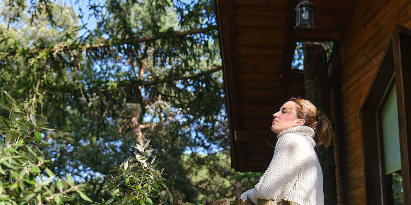 relaxed woman breathing nature's fresh air in a tree house in the middle of the forest