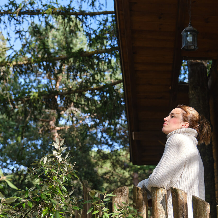 relaxed woman breathing nature's fresh air in a tree house in the middle of the forest