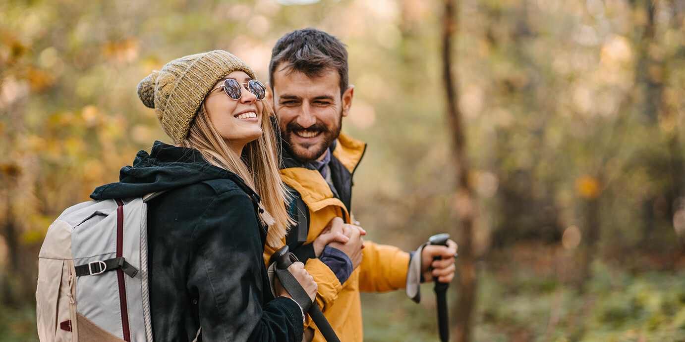 Young couple hiking. Hugging and smiling while walking and having a good time together