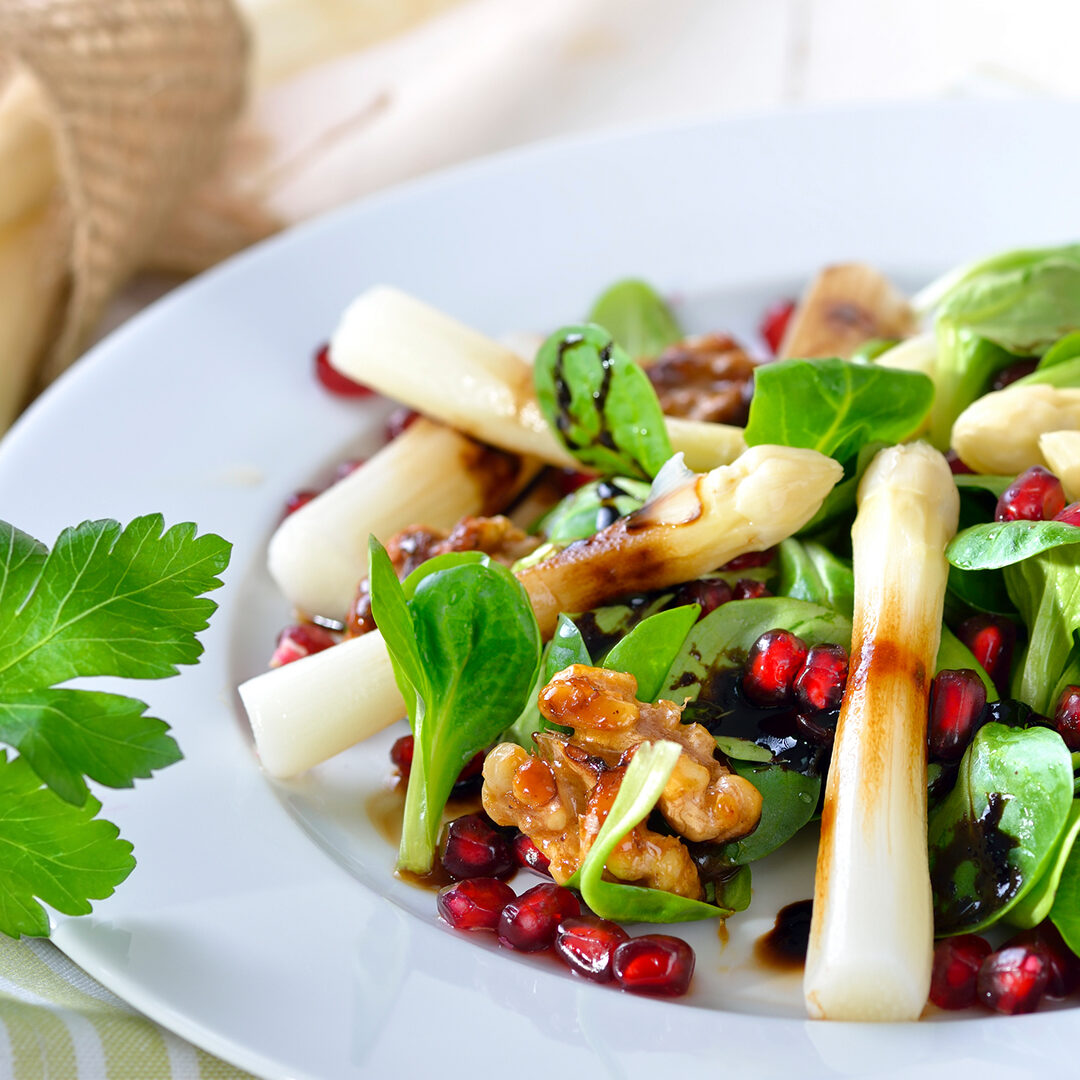 White asparagus on lamb's lettuce with candied walnuts, pomegranate seeds and balsamic vinegar