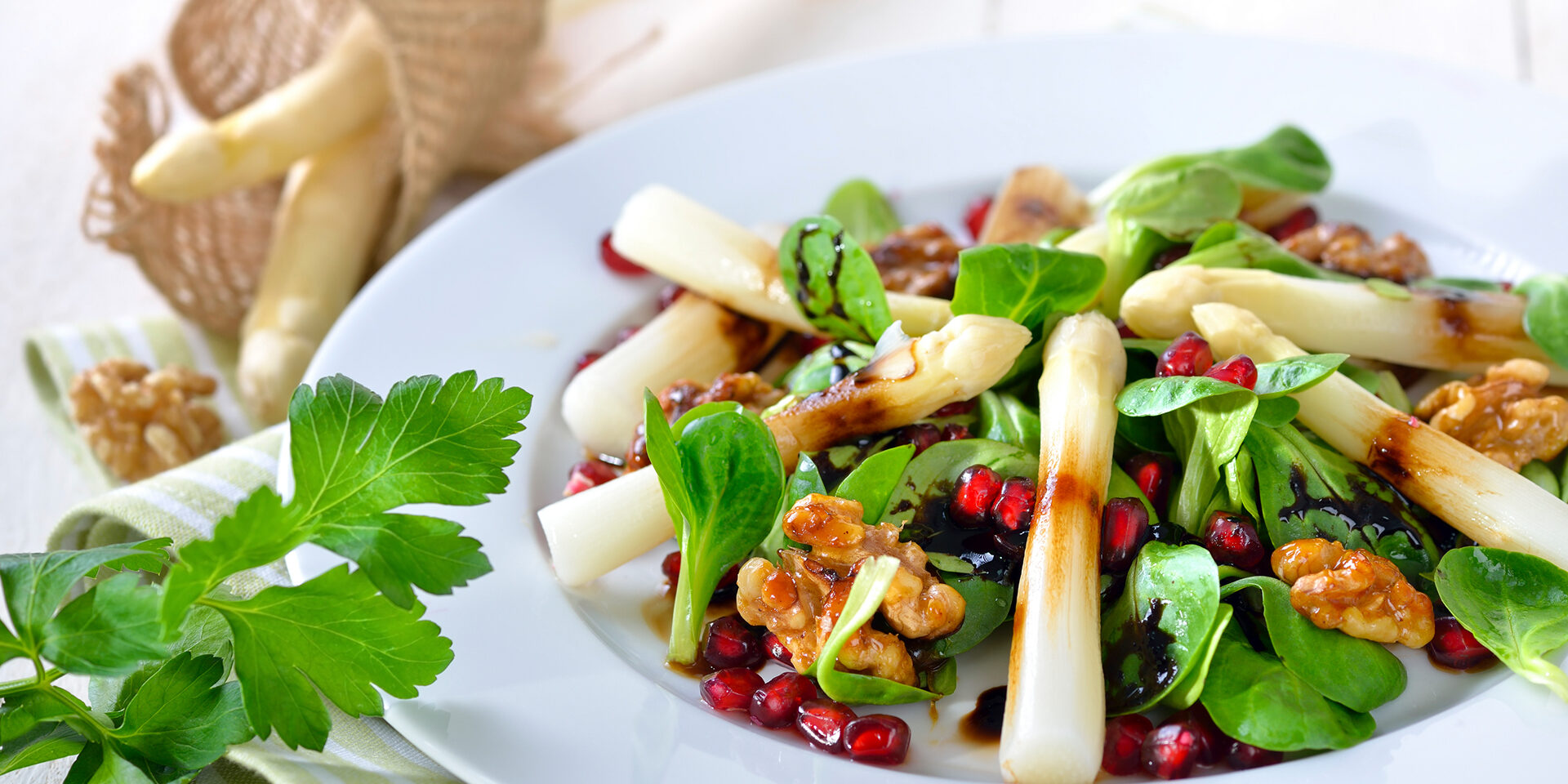 Salad with asparagus White asparagus on lamb's lettuce with candied walnuts, pomegranate seeds and balsamic vinegar