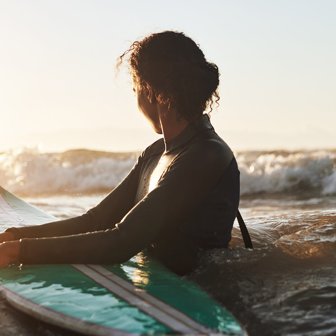 Shot of a beautiful young woman surfing in the ocean