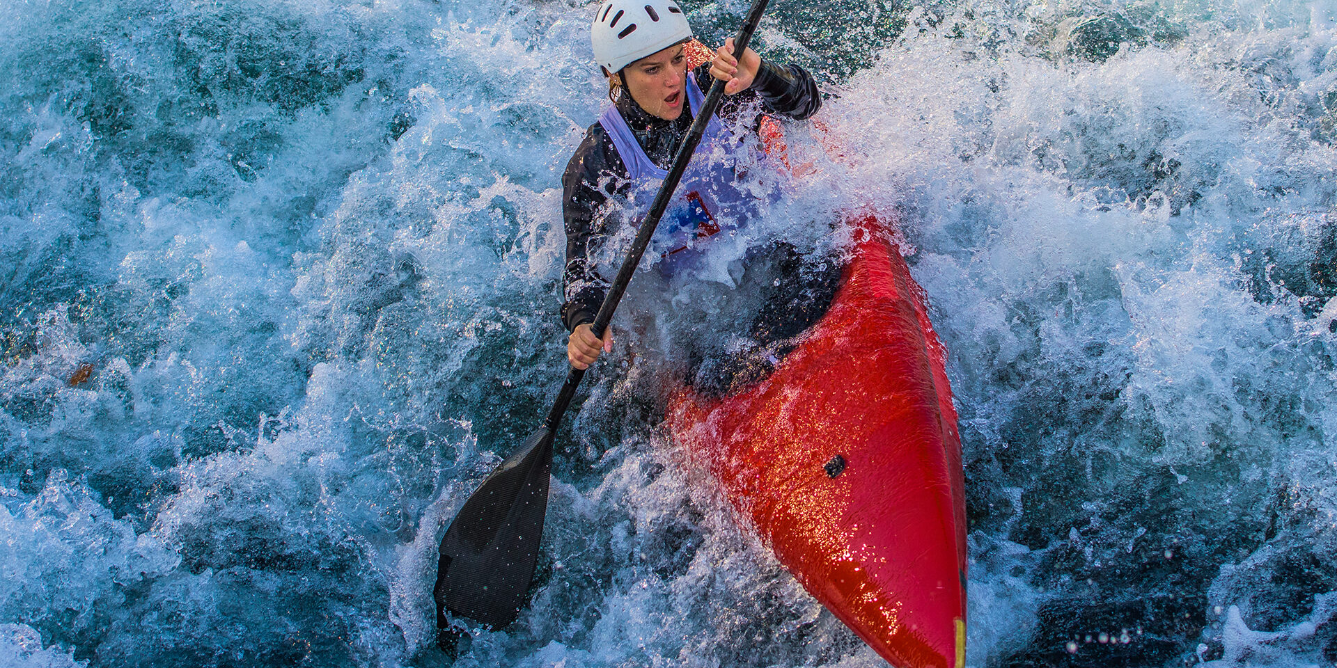 Woman rowing oar while enjoying kayaking in white water.