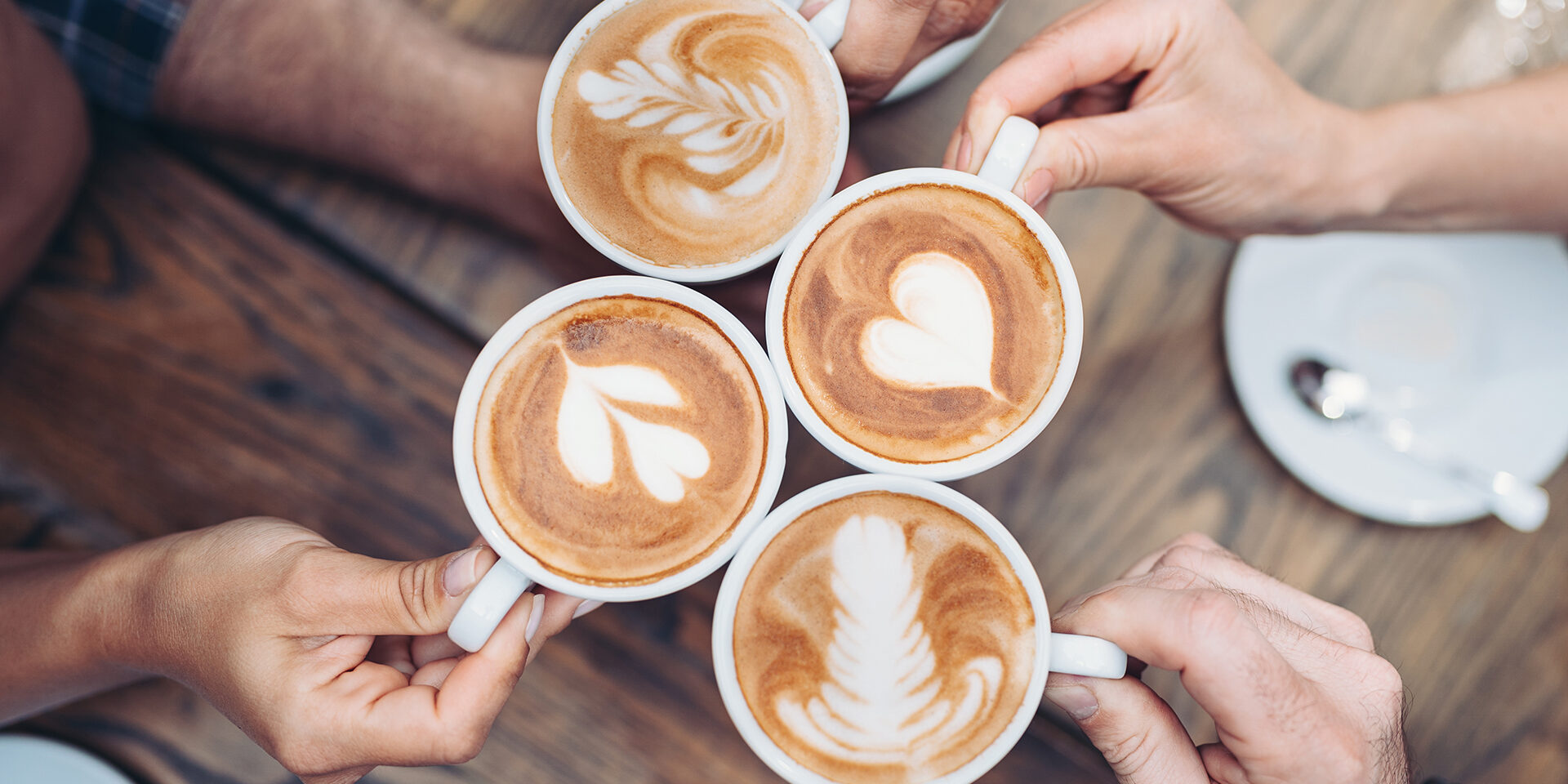Above view of hands holding cappuccino cups