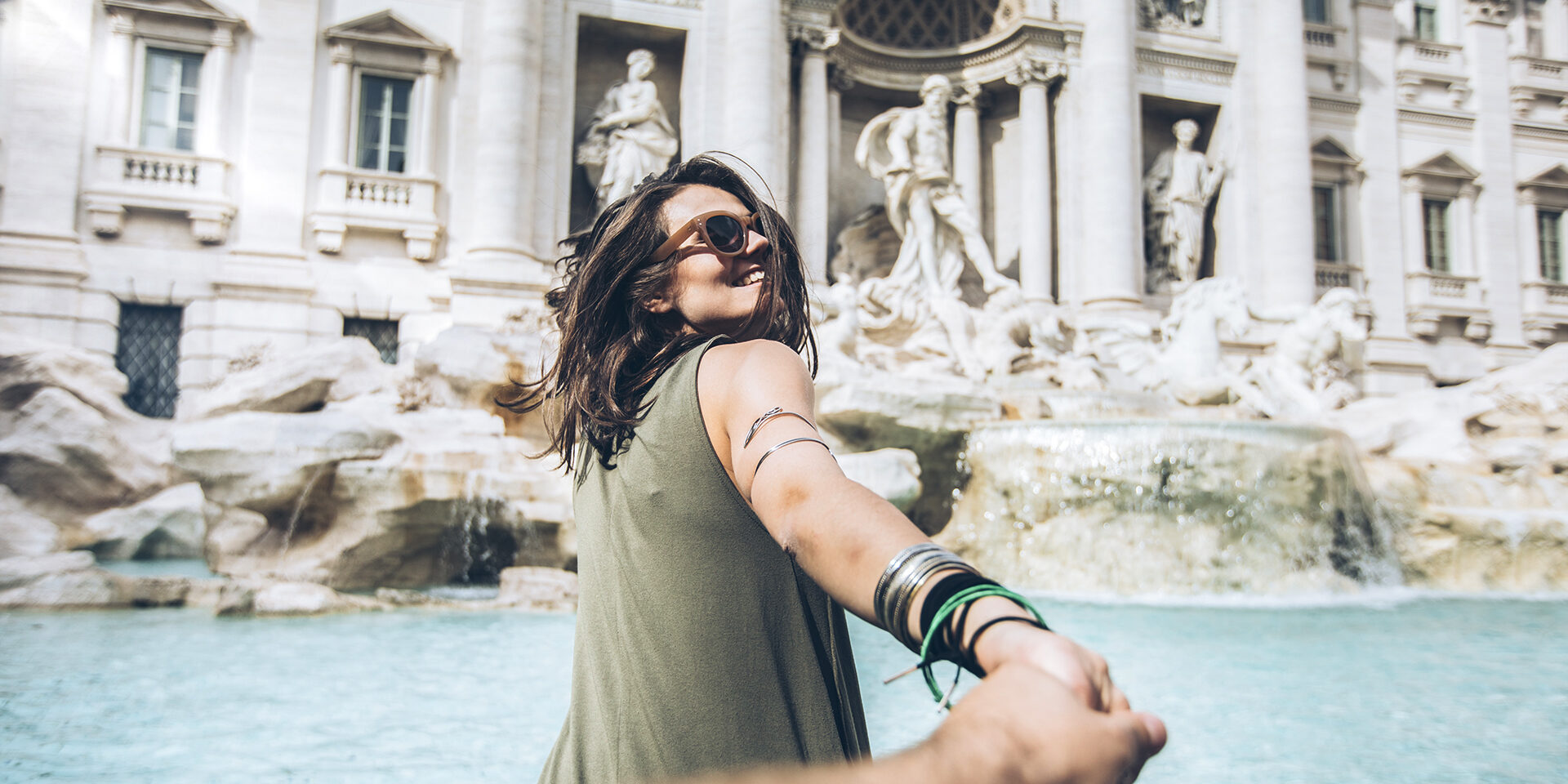 Young woman taking follow me picture in front of Trevi fountain in Rome