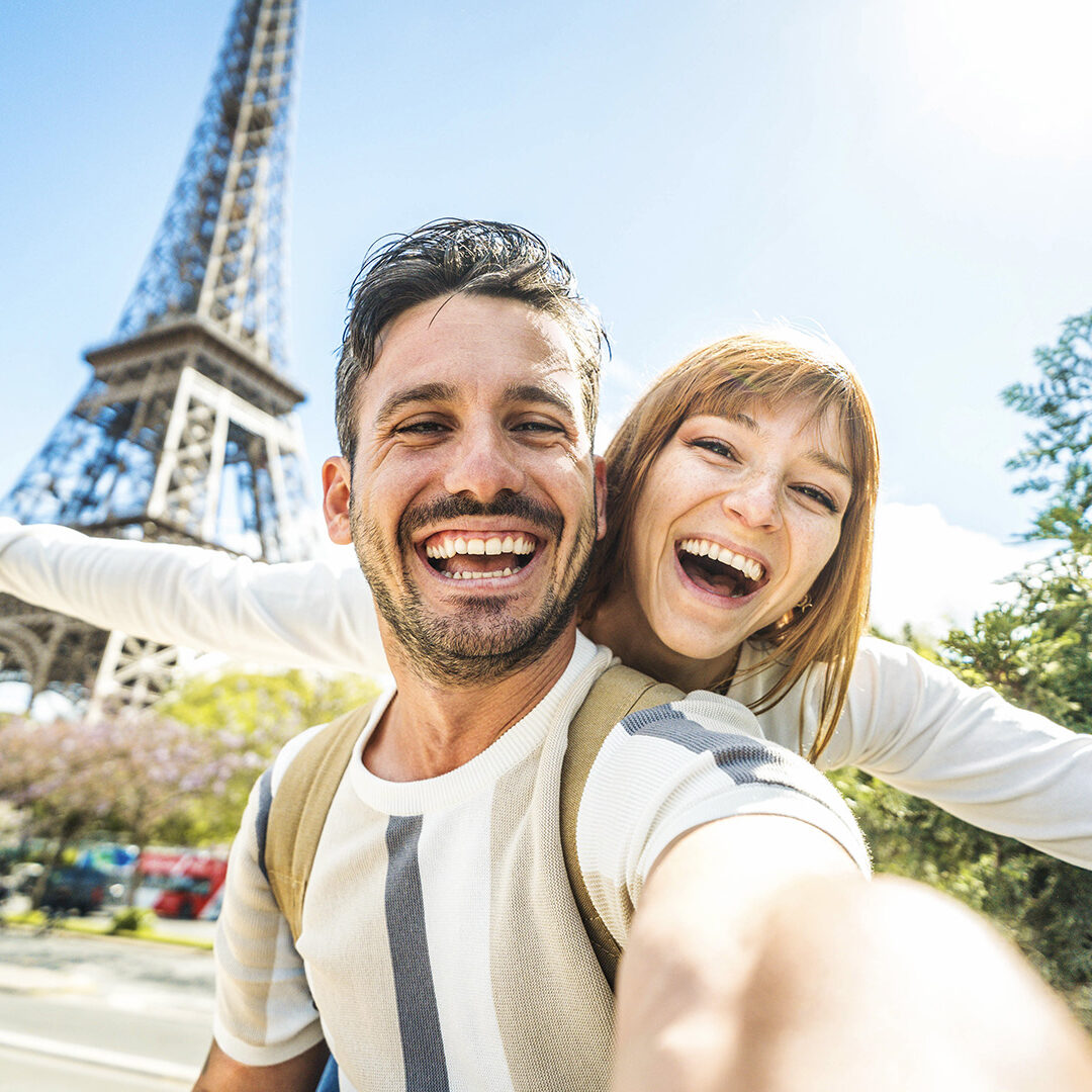 Happy couple of tourists taking selfie picture in front of Eiffel Tower in Paris, France - Travel and summer vacation life style concept