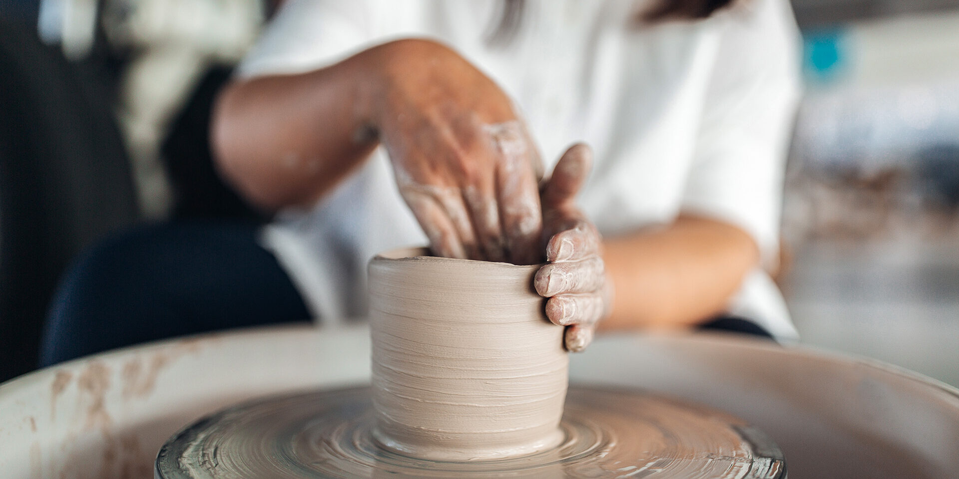 Woman sculpts an object on a potter's wheel