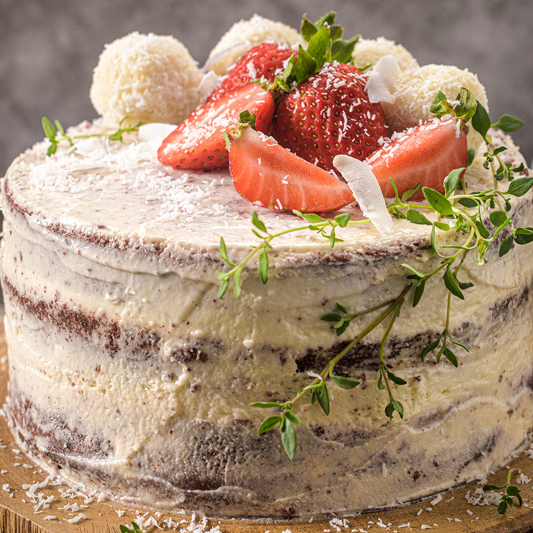 Naked cake with strawberries on kitchen counter top.