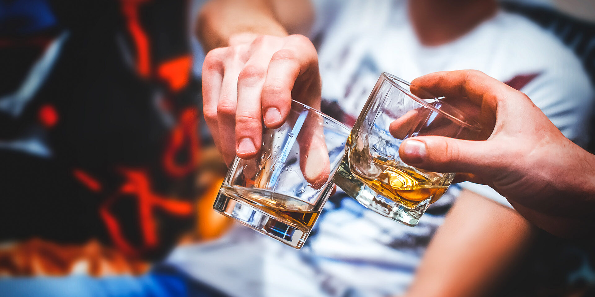 Two hands with whiskey Two hands clink glasses of whiskey at home,on the couch, cozy
