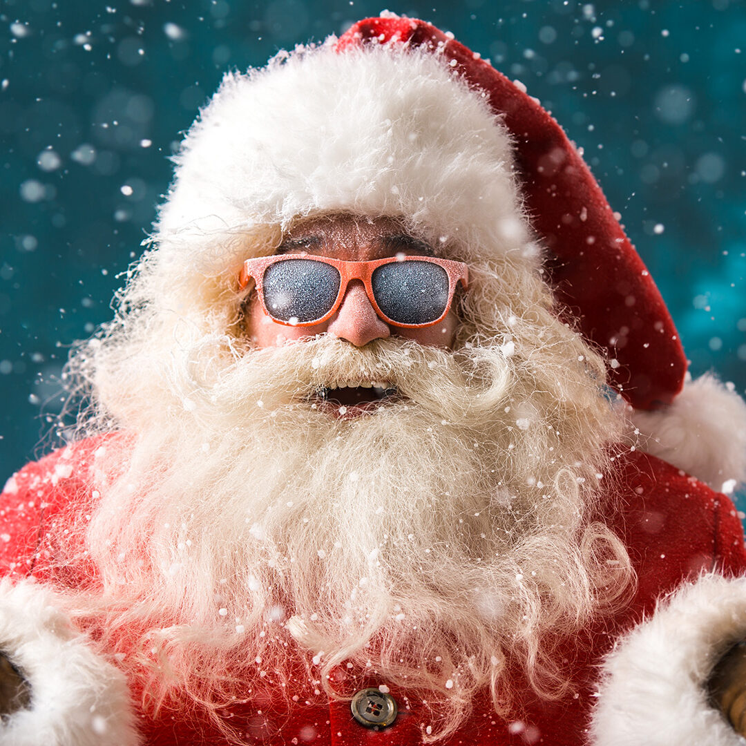 Santa Claus wearing sunglasses dancing outdoors at North Pole in snowfall. He is celebrating Christmas after hard work