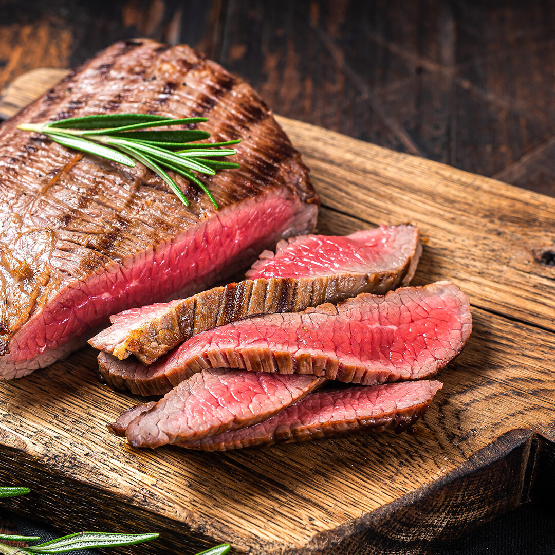 Barbecue dry aged wagyu Flank Steak on a cutting board. Wooden background. Top view.