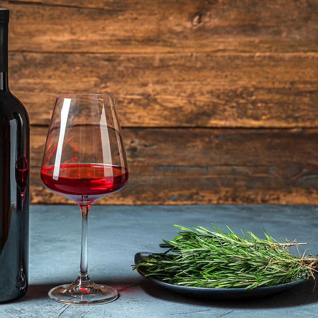 A bottle of wine and a glass of wine on a dark background. Side view, copy space.