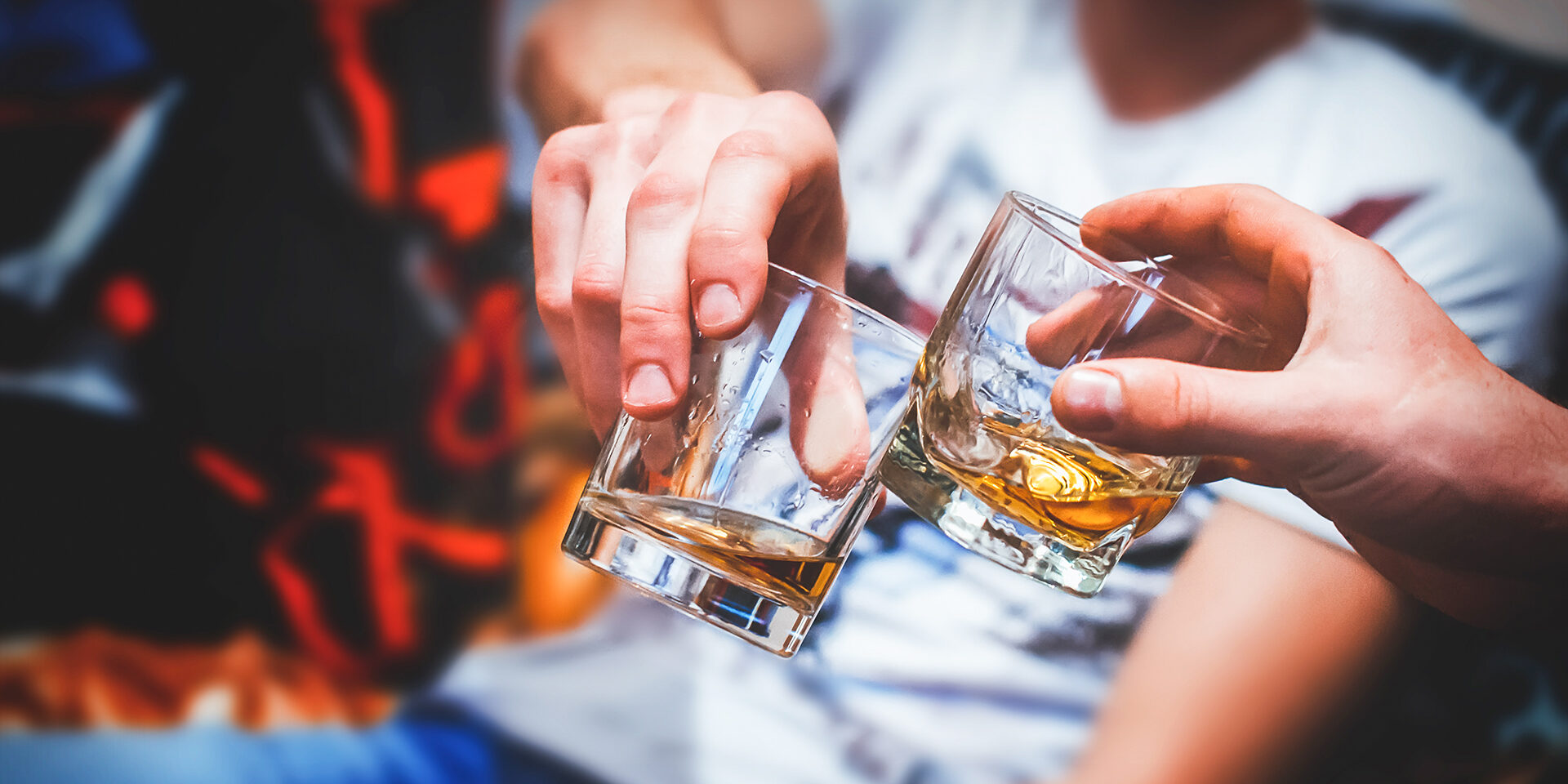 Two hands with whiskey Two hands clink glasses of whiskey at home,on the couch, cozy