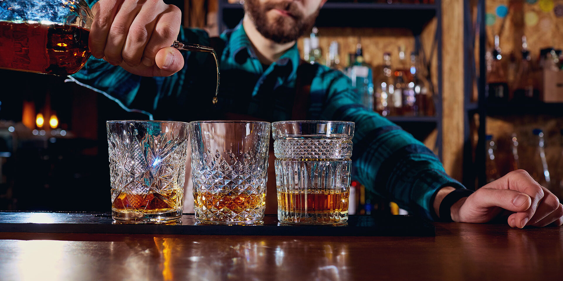 The barman pours alcohol into a glass. Close-up.