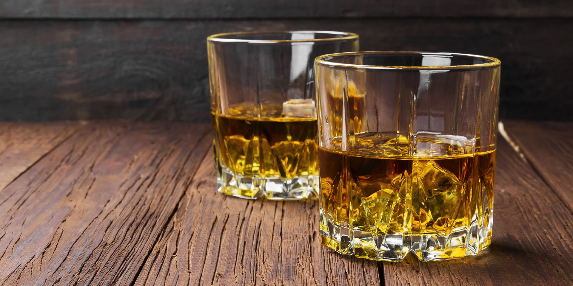 Whisky with ice in two glasses on a wooden background. Copy space. Food background Whisky with ice in two glasses on a wooden background. Copy space. Food background